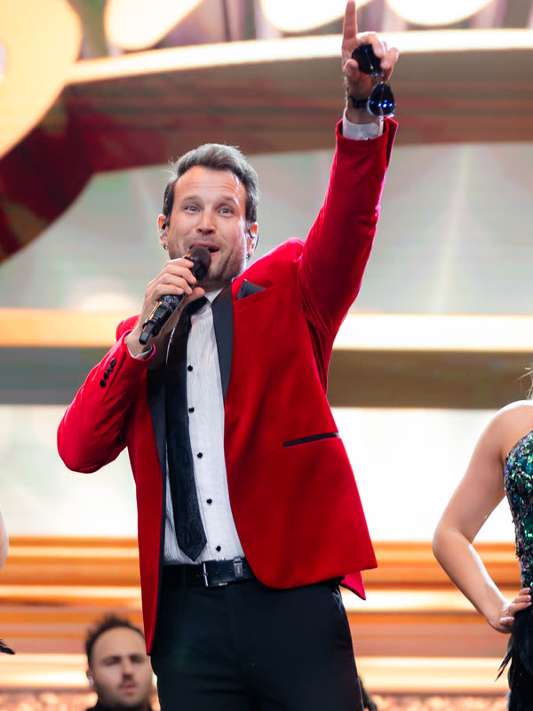 Sam in the red jacket singing and pointing to the crowd