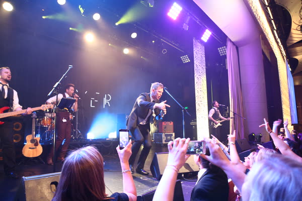 The singer crouched at the front of the stage pointing at fans who hold up their phones